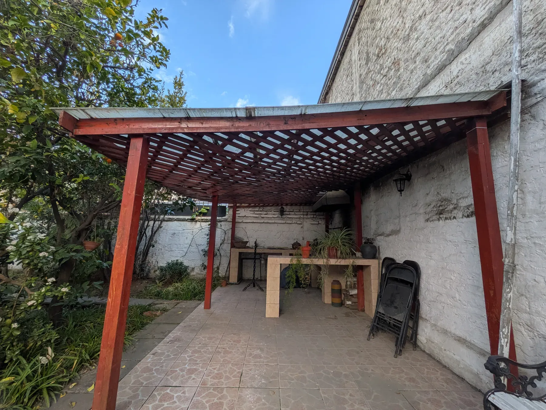 La pérgola antigua de madera pintada, sobre un patio en desuso