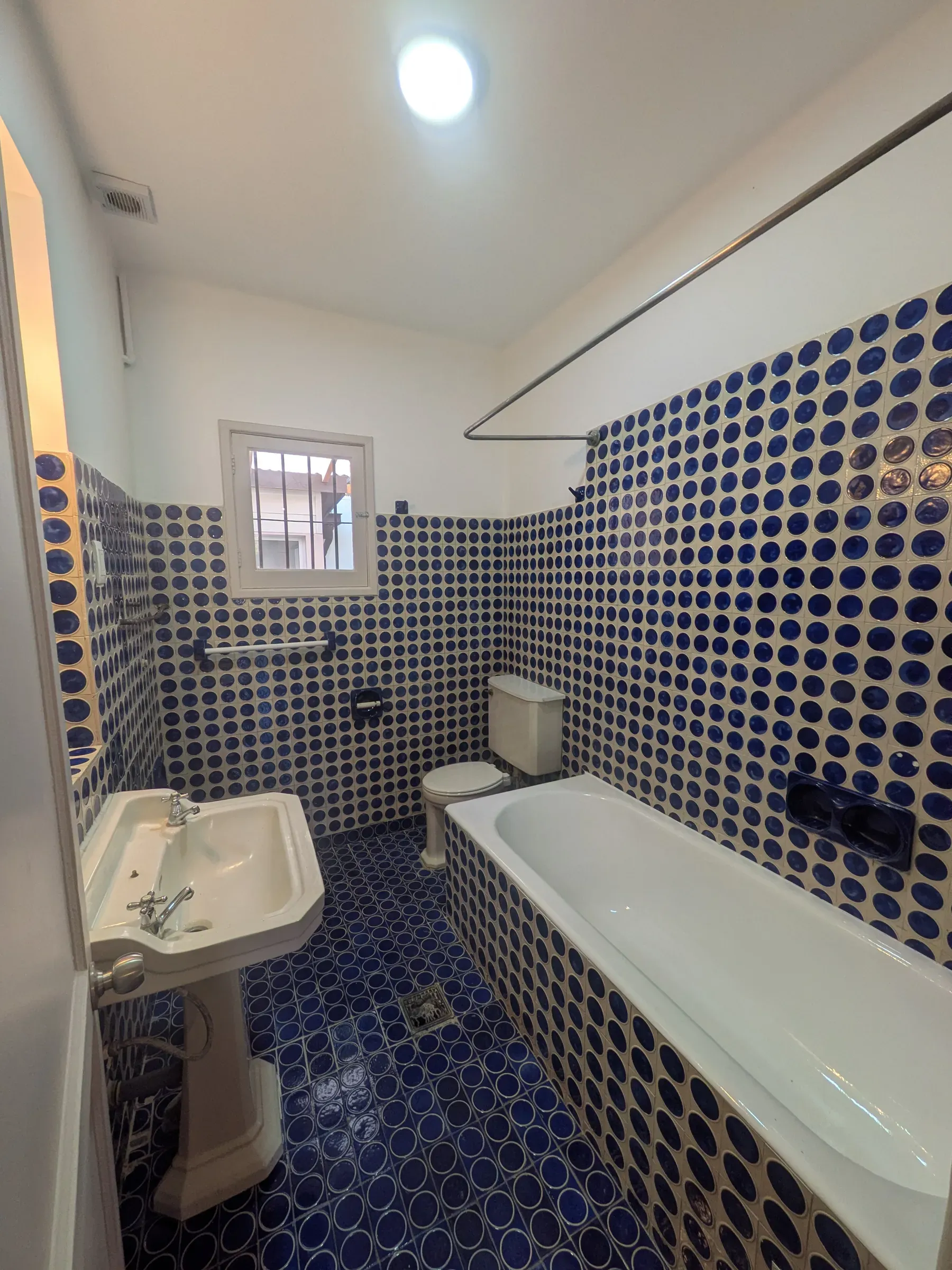 El baño terminado, con la tina esmaltada y el mosaico azul