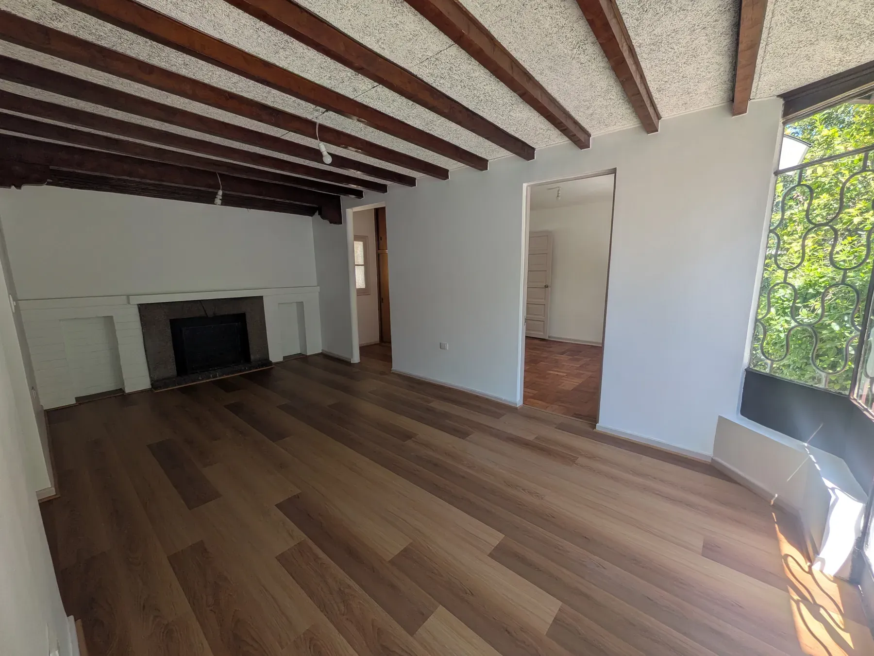 Salón con la chimenea, las vigas a la vista y el piso recuperado