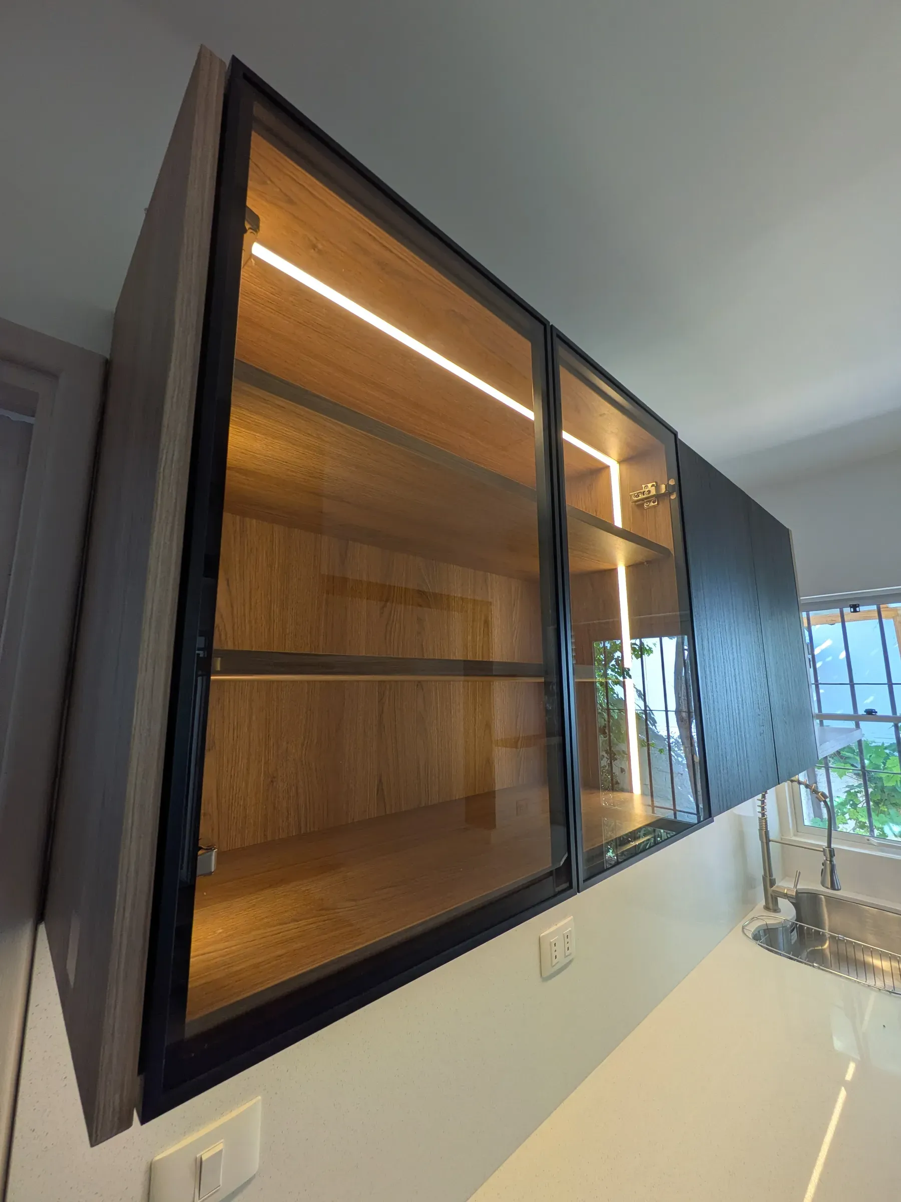 Vitrina iluminada de la cocina, con frente de vidrio y estantes de madera