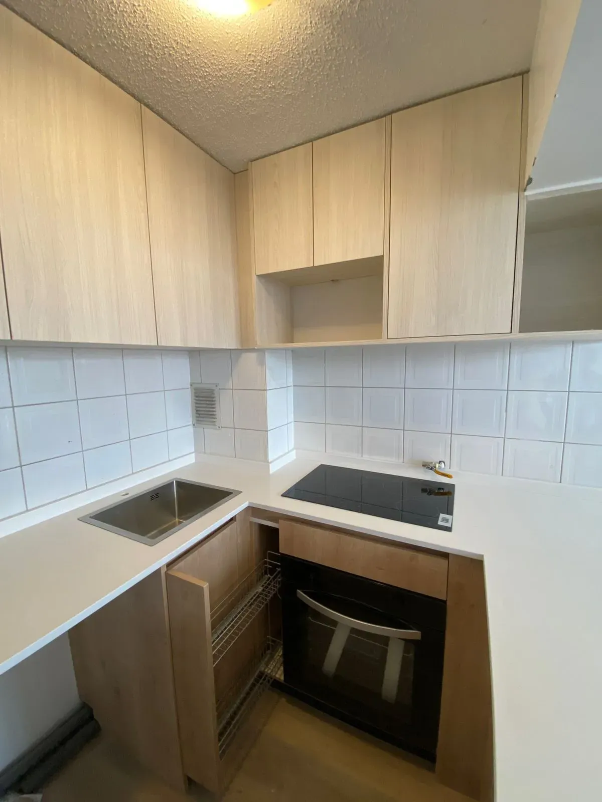 Cocina terminada: lavaplatos, encimera de inducción y horno empotrado bajo la cubierta