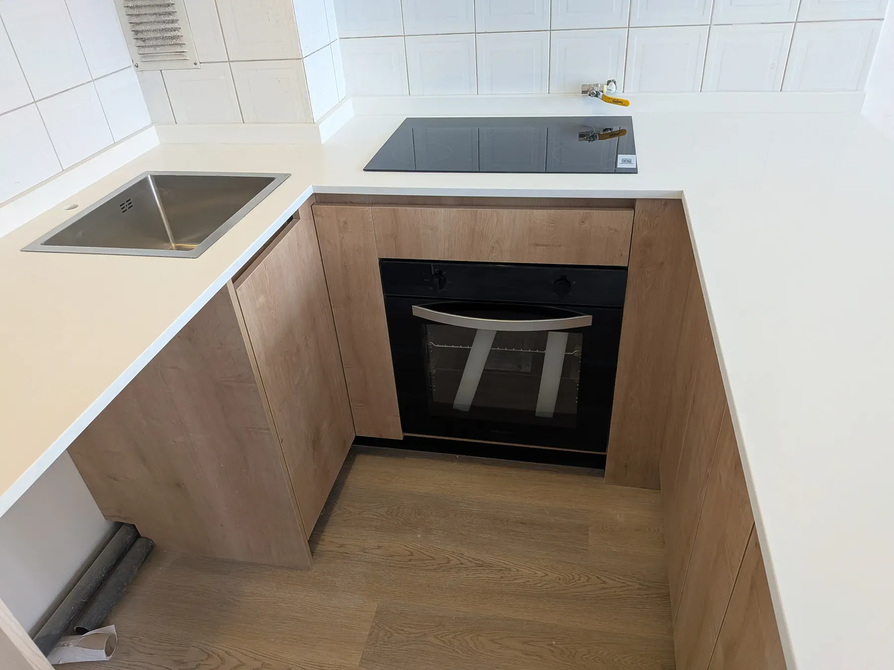 Detalle del lavaplatos, la encimera de inducción y el horno ya instalados